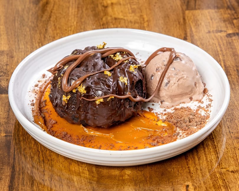 Chocolate lava cake with gold flakes, chocolate drizzle, caramel, and a scoop of ice cream.